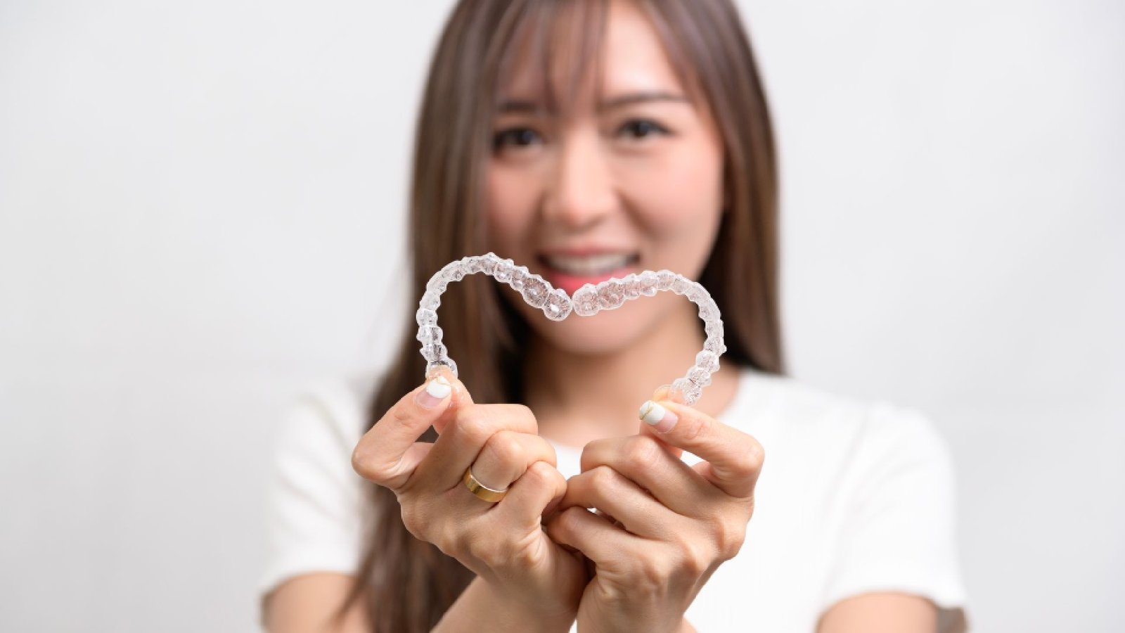 Smiling patient holding clear aligners